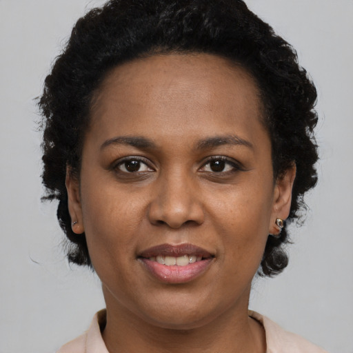 Joyful black young-adult female with short  black hair and brown eyes