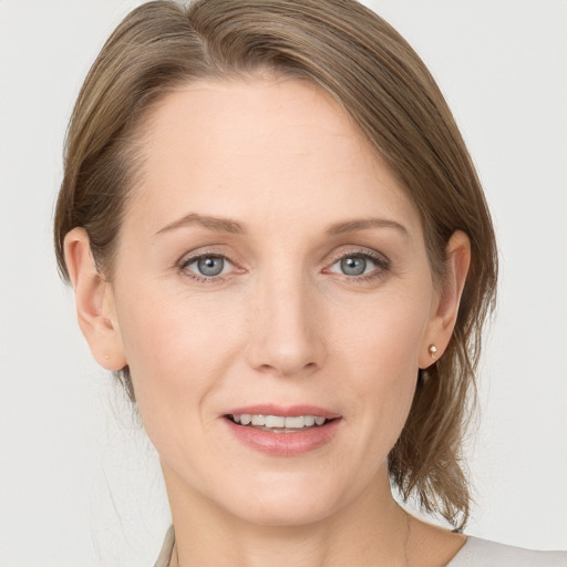 Joyful white young-adult female with medium  brown hair and grey eyes