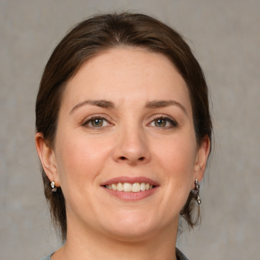 Joyful white young-adult female with medium  brown hair and grey eyes