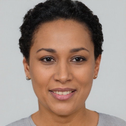 Joyful black young-adult female with short  black hair and brown eyes