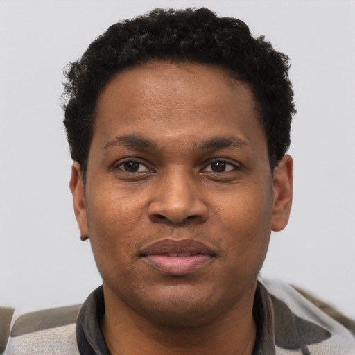 Joyful black young-adult male with short  black hair and brown eyes