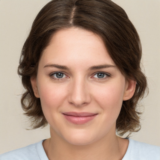 Joyful white young-adult female with medium  brown hair and green eyes