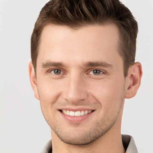 Joyful white young-adult male with short  brown hair and grey eyes