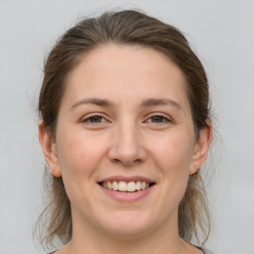 Joyful white young-adult female with medium  brown hair and grey eyes