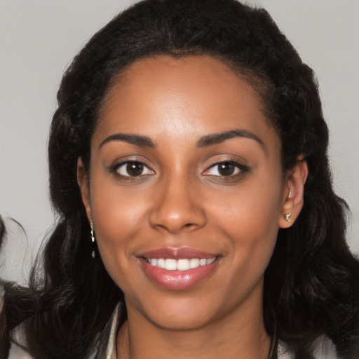 Joyful black young-adult female with long  black hair and brown eyes