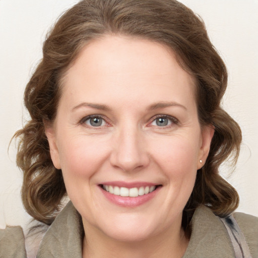 Joyful white adult female with medium  brown hair and green eyes