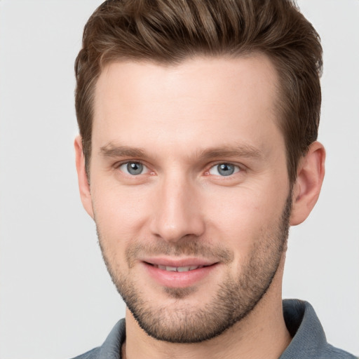 Joyful white young-adult male with short  brown hair and grey eyes