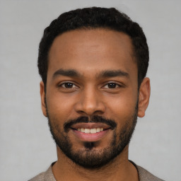 Joyful black young-adult male with short  black hair and brown eyes