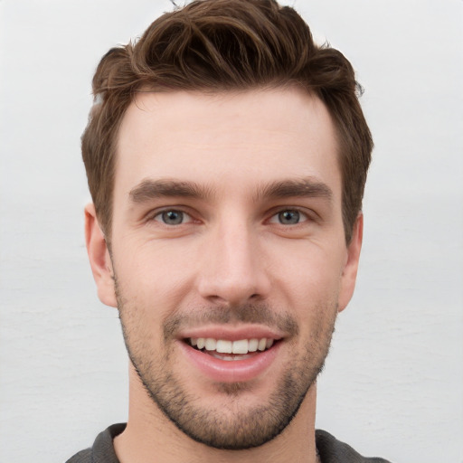 Joyful white young-adult male with short  brown hair and grey eyes