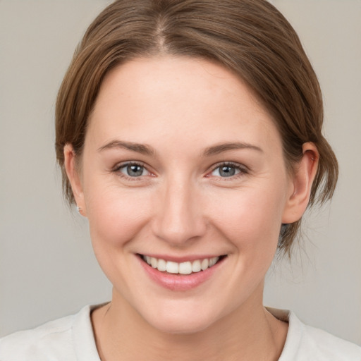 Joyful white young-adult female with medium  brown hair and grey eyes