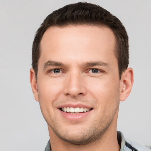 Joyful white young-adult male with short  brown hair and grey eyes