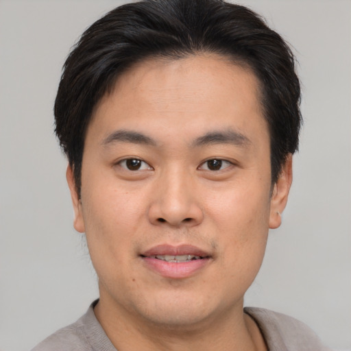 Joyful asian young-adult male with short  brown hair and brown eyes