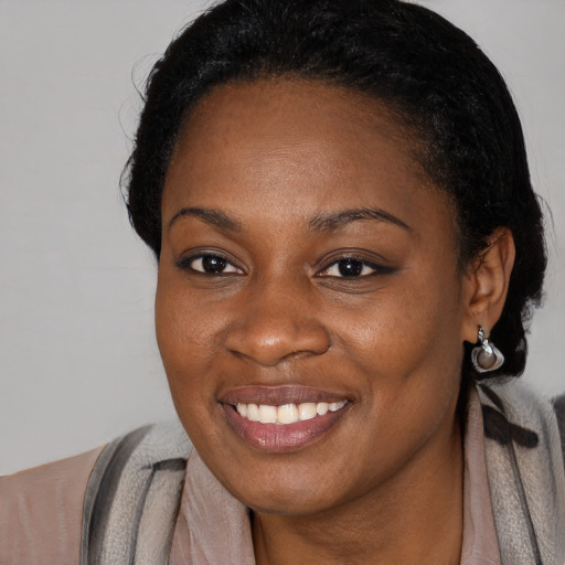 Joyful black young-adult female with long  black hair and brown eyes