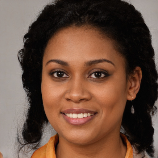 Joyful black young-adult female with long  brown hair and brown eyes