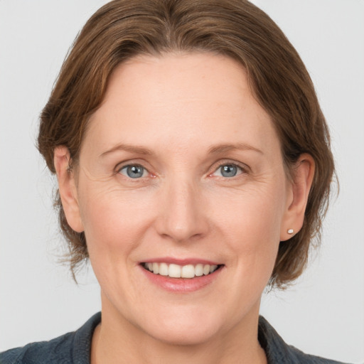 Joyful white adult female with medium  brown hair and grey eyes