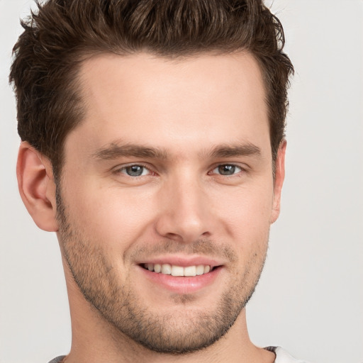 Joyful white young-adult male with short  brown hair and grey eyes