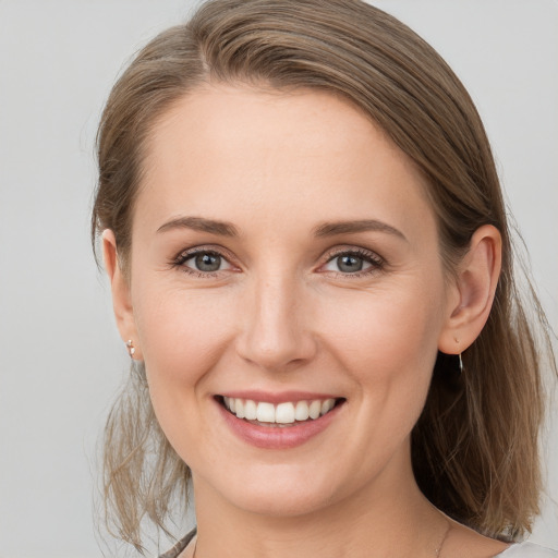 Joyful white young-adult female with medium  brown hair and grey eyes