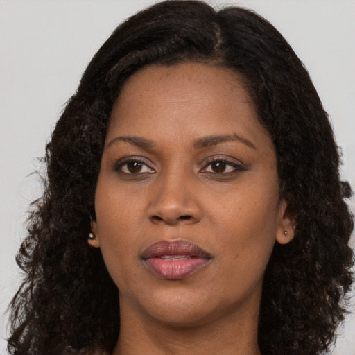Joyful black young-adult female with long  brown hair and brown eyes