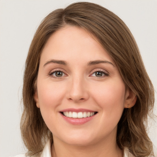 Joyful white young-adult female with medium  brown hair and green eyes