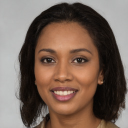 Joyful black young-adult female with long  brown hair and brown eyes