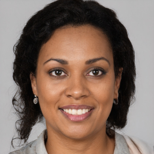 Joyful black young-adult female with long  brown hair and brown eyes