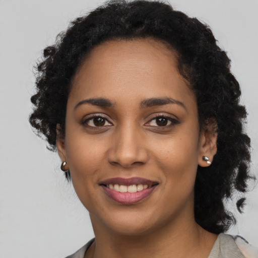 Joyful black young-adult female with long  black hair and brown eyes