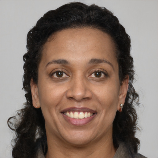 Joyful black adult female with long  brown hair and brown eyes