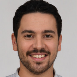 Joyful white young-adult male with short  black hair and brown eyes