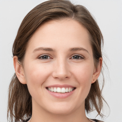 Joyful white young-adult female with medium  brown hair and grey eyes