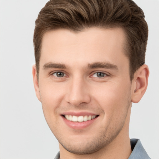 Joyful white young-adult male with short  brown hair and grey eyes