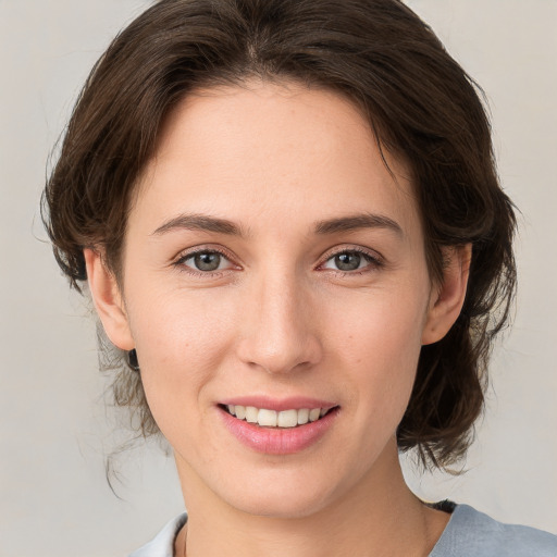 Joyful white young-adult female with medium  brown hair and grey eyes