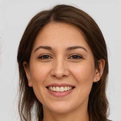 Joyful white adult female with long  brown hair and brown eyes