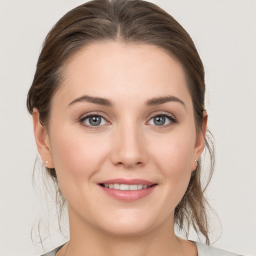 Joyful white young-adult female with medium  brown hair and grey eyes