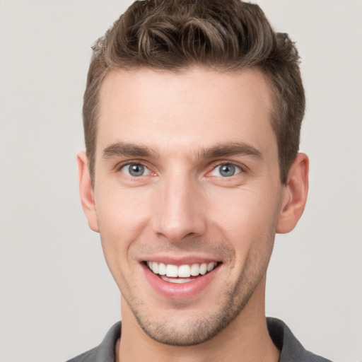 Joyful white young-adult male with short  brown hair and grey eyes