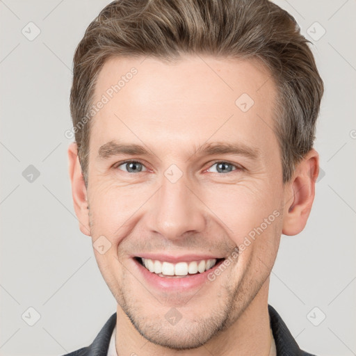 Joyful white young-adult male with short  brown hair and grey eyes