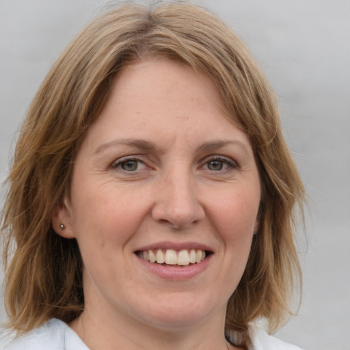 Joyful white adult female with medium  brown hair and blue eyes