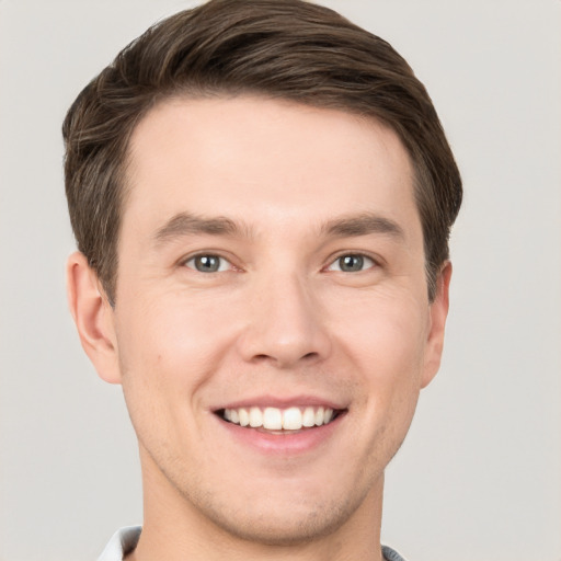 Joyful white young-adult male with short  brown hair and grey eyes