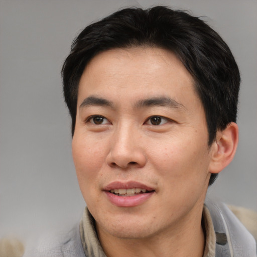 Joyful asian adult male with short  brown hair and brown eyes