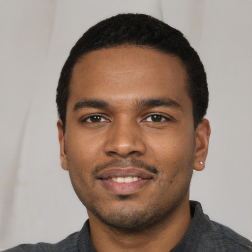 Joyful black young-adult male with short  black hair and brown eyes