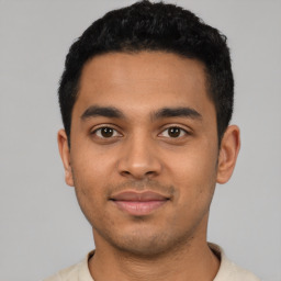 Joyful latino young-adult male with short  black hair and brown eyes