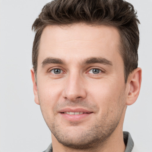 Joyful white young-adult male with short  brown hair and grey eyes