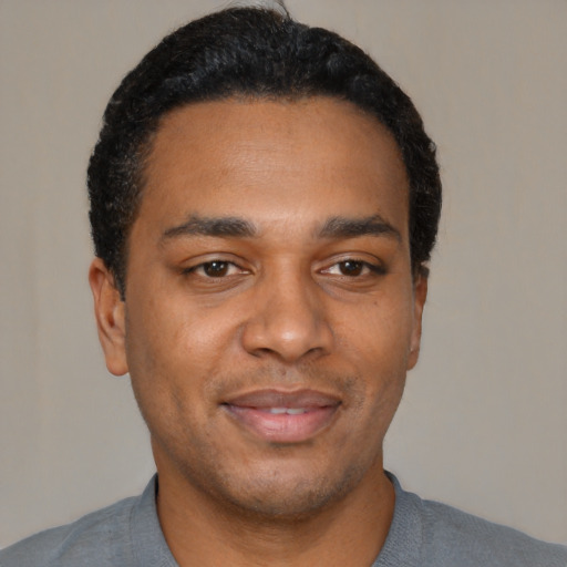 Joyful black young-adult male with short  black hair and brown eyes