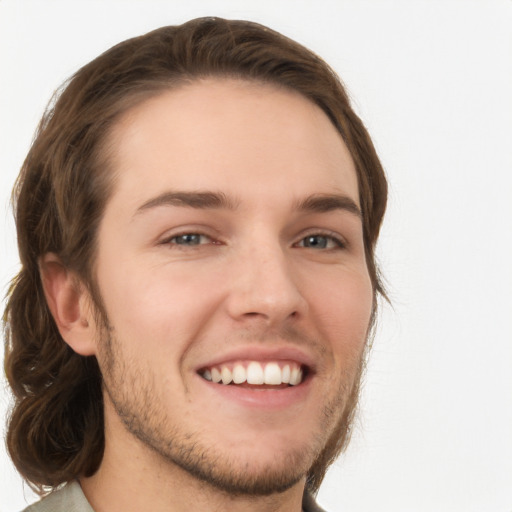 Joyful white young-adult male with long  brown hair and grey eyes