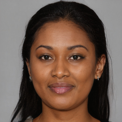 Joyful black young-adult female with long  brown hair and brown eyes