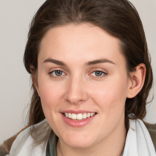 Joyful white young-adult female with medium  brown hair and grey eyes