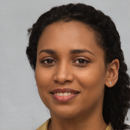 Joyful black young-adult female with long  black hair and brown eyes