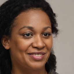 Joyful black young-adult female with long  brown hair and brown eyes