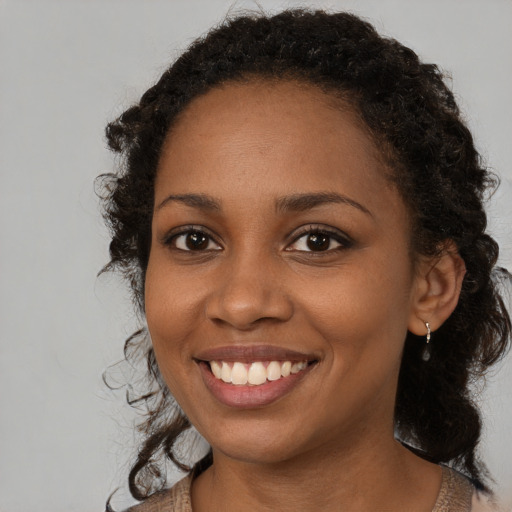 Joyful black young-adult female with long  brown hair and brown eyes