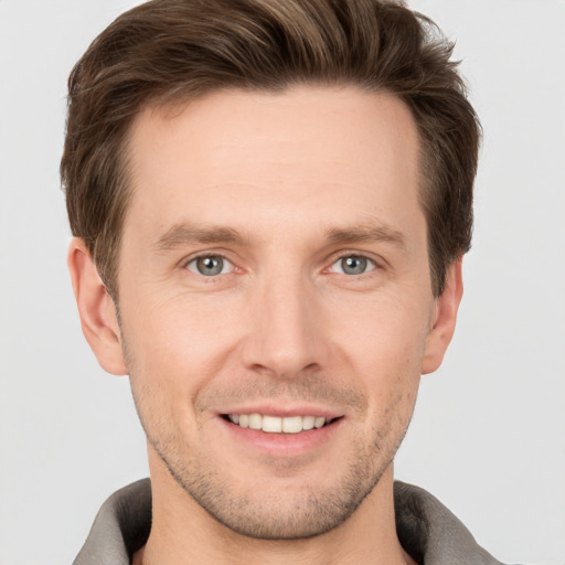 Joyful white young-adult male with short  brown hair and grey eyes