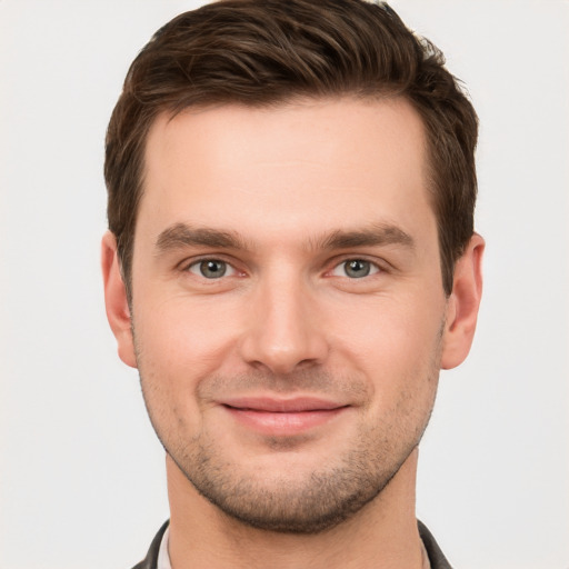 Joyful white young-adult male with short  brown hair and grey eyes